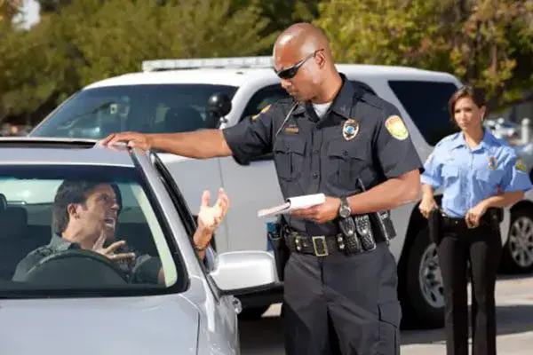 A police officer is handing out fliers to motorists.