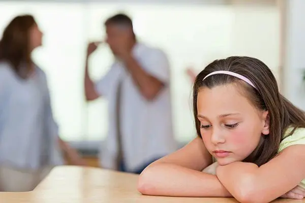 A young girl sitting at the table with her arms crossed.